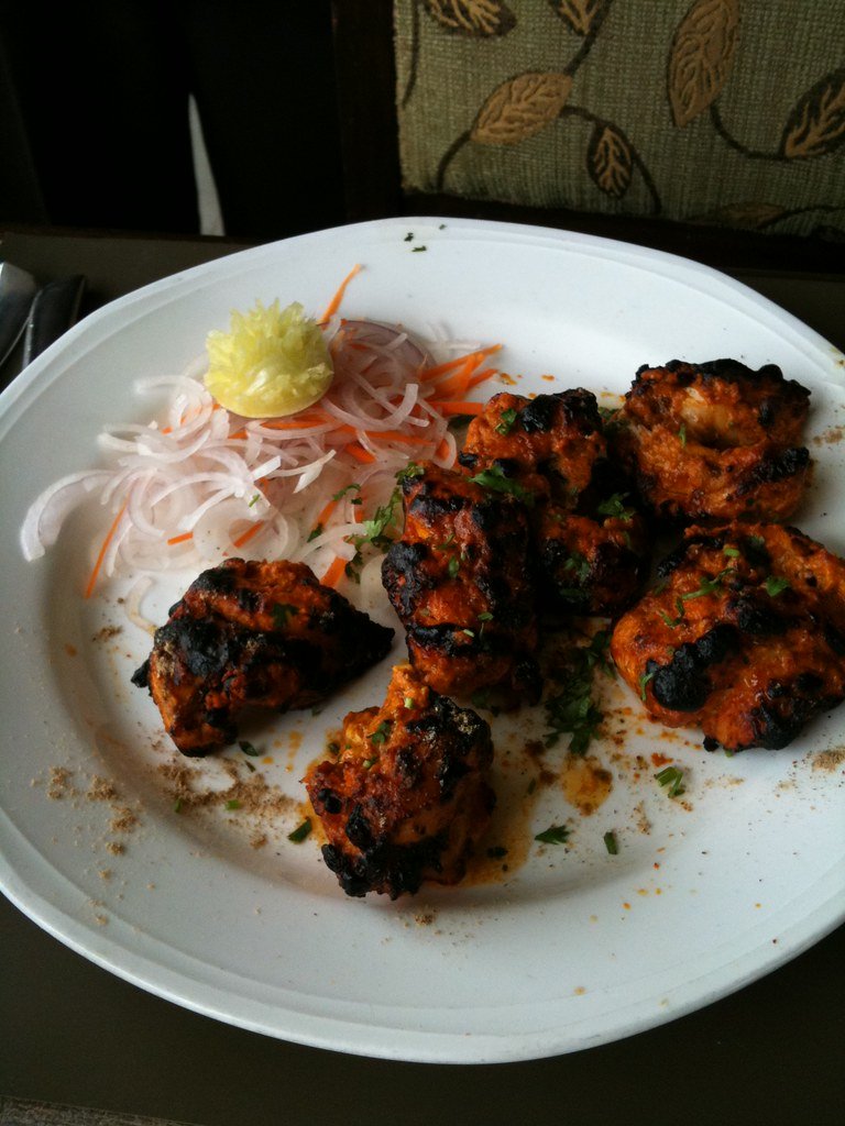 Chicken tikka pieces with charred edges on a plate