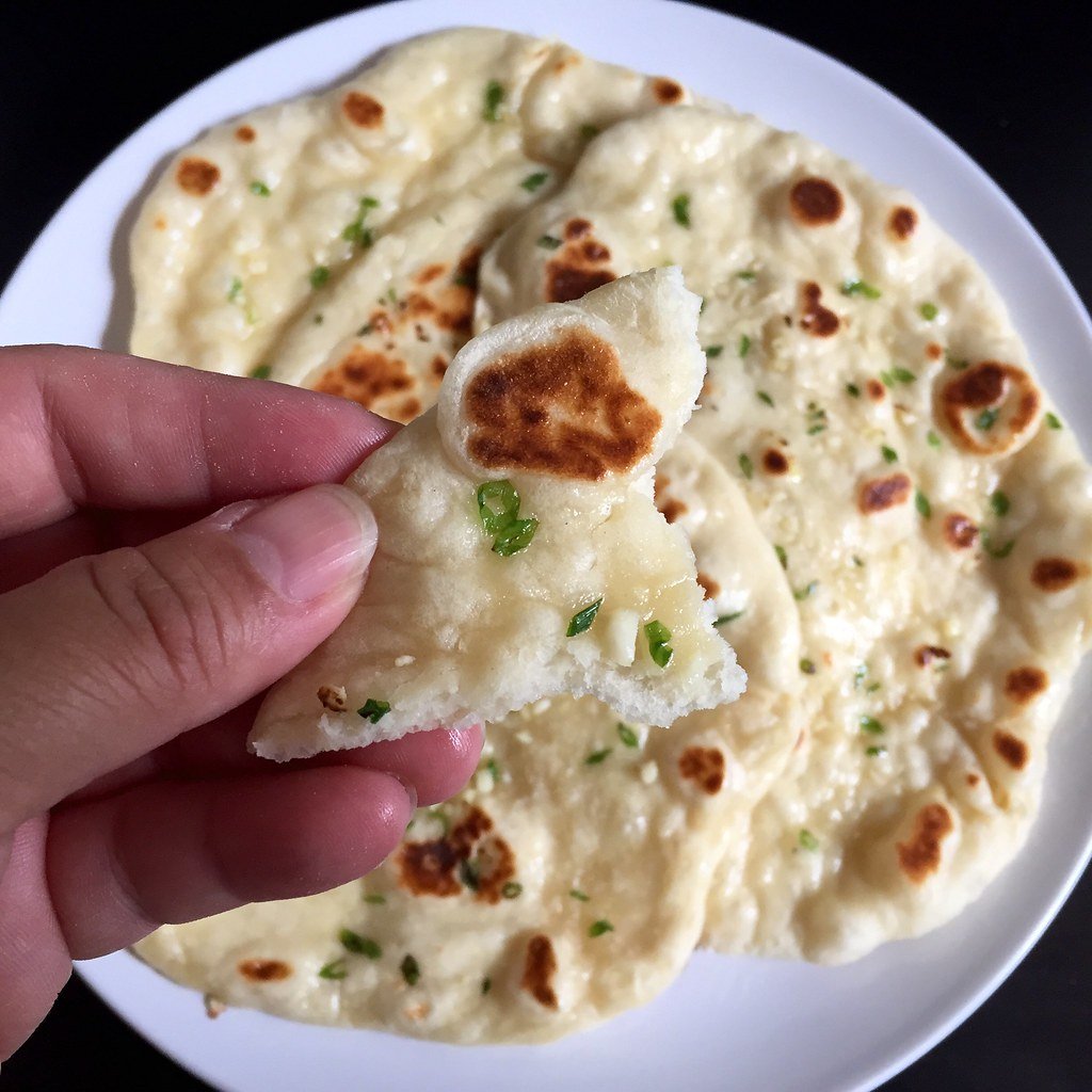 Garlic naan bread topped with chopped garlic and coriander