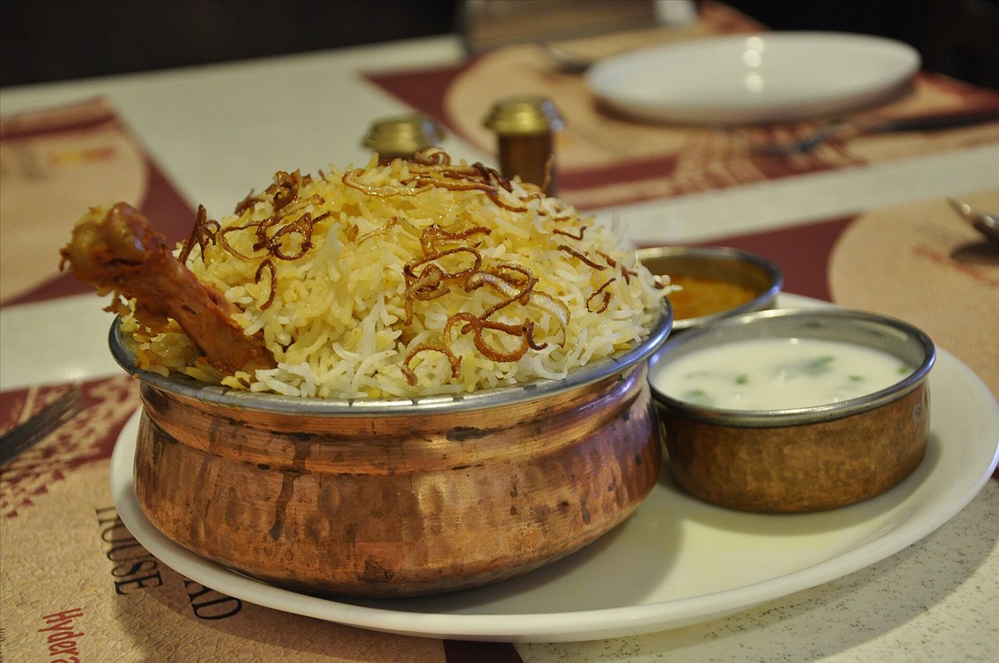A steaming serving of Hyderabadi chicken dum biryani garnished with fried onions, mint and boiled egg